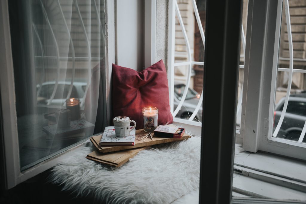 cozy candles and pillows in window
