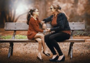 mother and daughter talking on bench