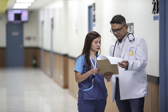 doctor and nurse looking at a medical file in a hospital hallway