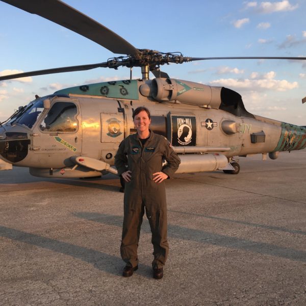 Woman in military uniform standing in front of military helicopter