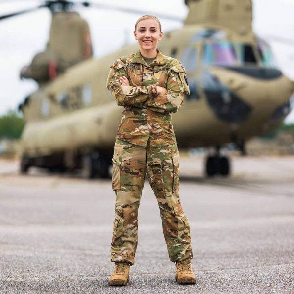 Woman standing in military uniform in front of military helicopter