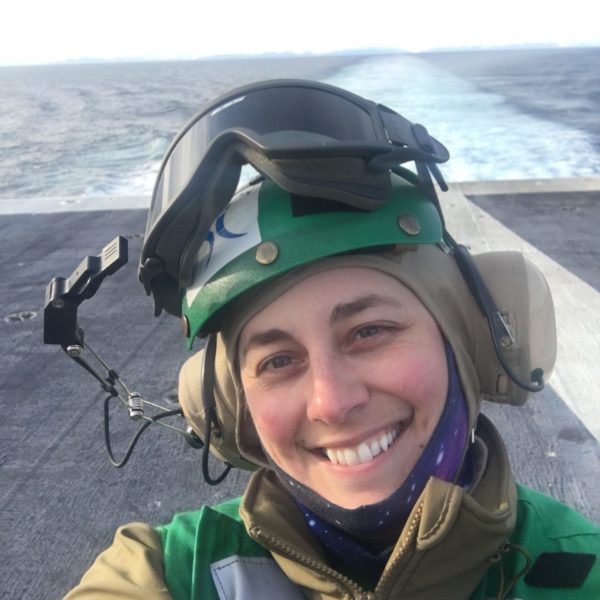 Woman standing on flight deck of aircraft carrier in unifrom