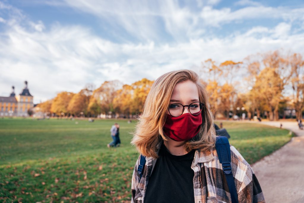 college student on green campus wearing a mask