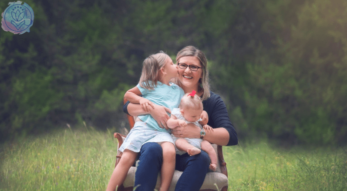 mother hugging 2 daughters on a chair in a field