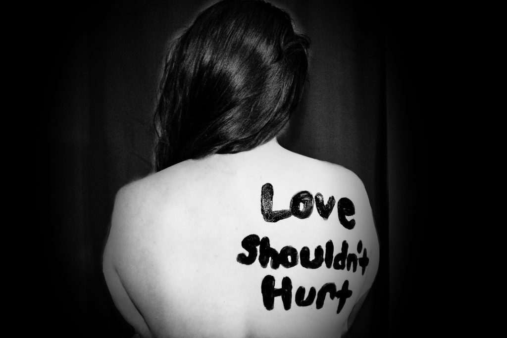 woman with "love shouldn't hurt" on back