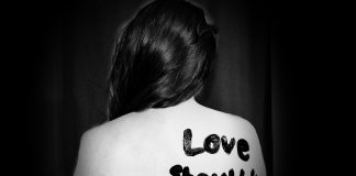 woman with "love shouldn't hurt" on back
