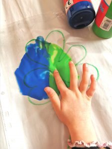 toddler hand doing finger painting through a plastic bag
