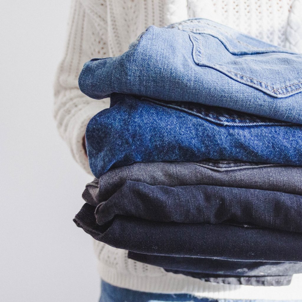 person holding a stack of jeans