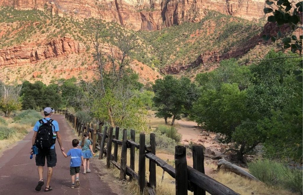 A man and two kids walk a trail in Zion National Park