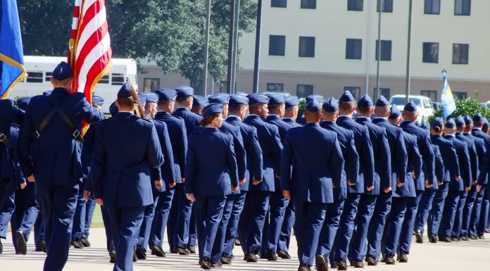 air force military airmen in blues marching with American flag