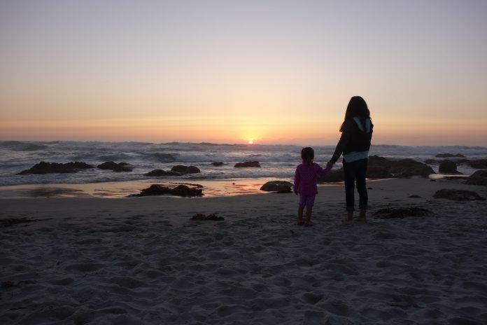 mom and daughter holding hands on a beach