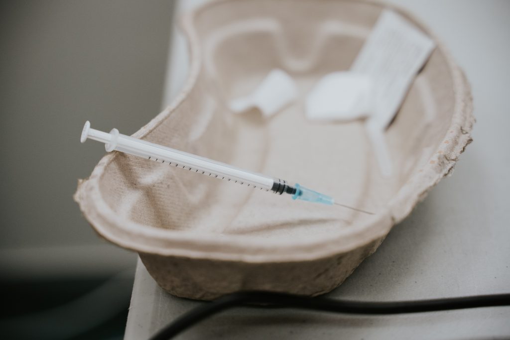 paper emesis bowl with a syringe indicating a vaccine