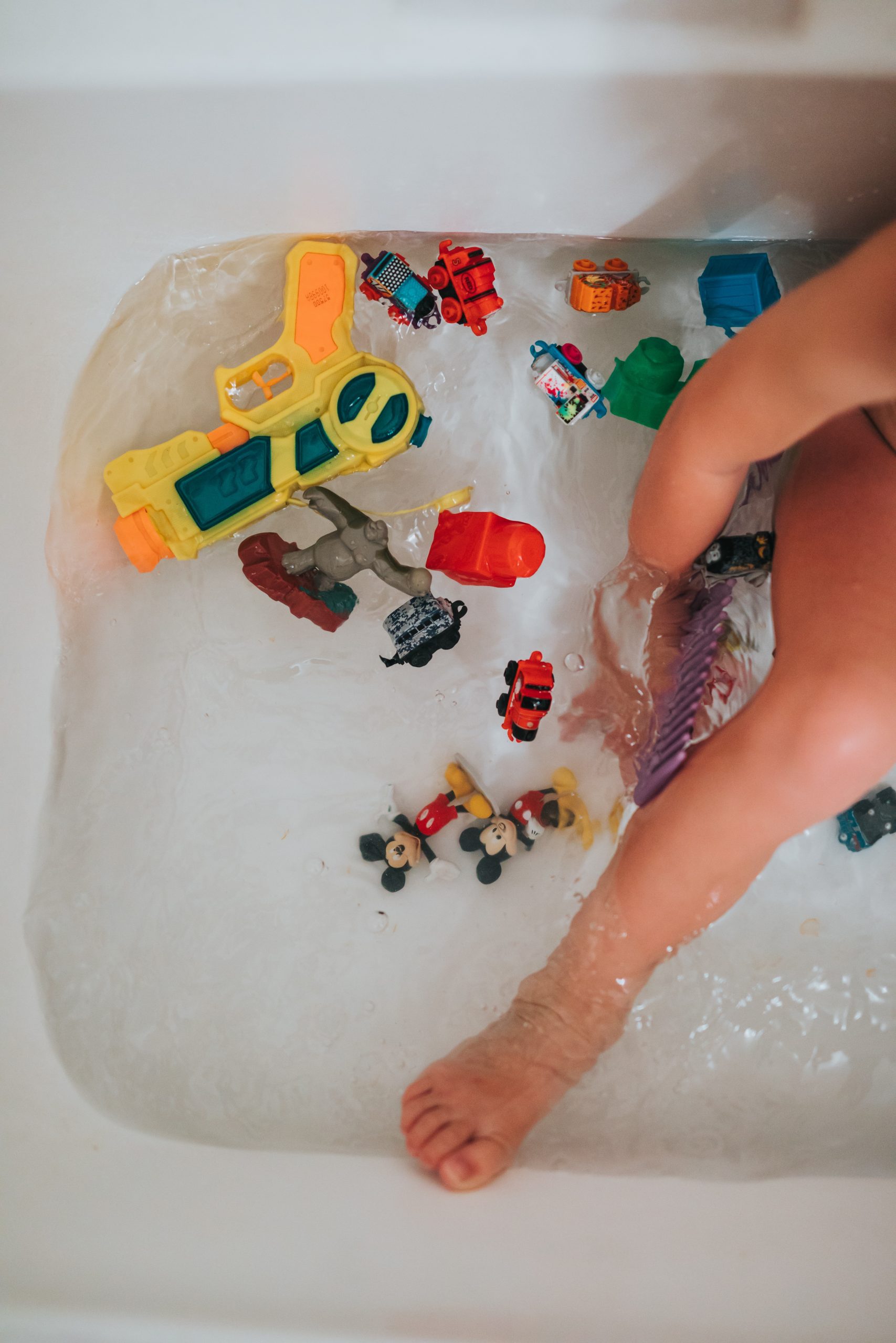 toys in a white bathtub with a small child