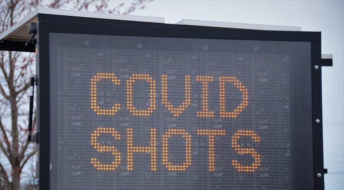 large letter board with "COVID SHOTS" on screen