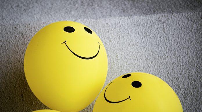 three yellow balloons with smiley faces on them