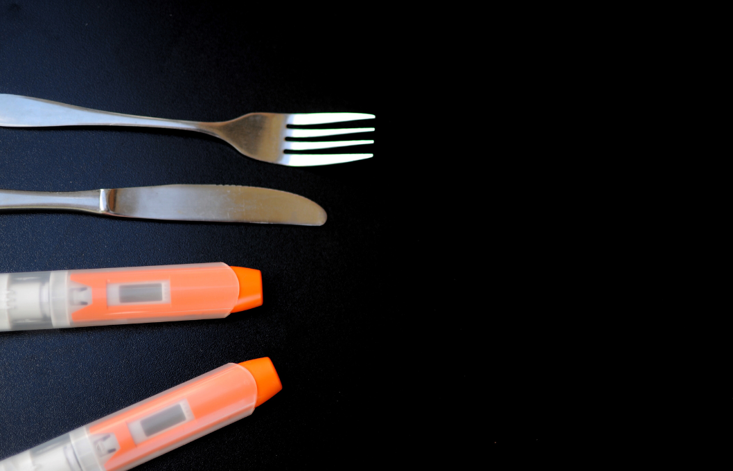 black background with fork, knife, and 2 EpiPens for allergic reaction