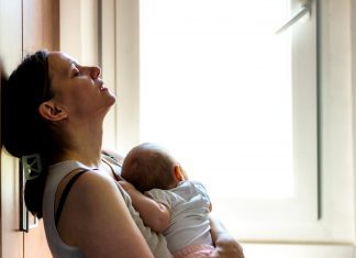 Woman holding infant appearing tired, concerned, sad, depressed