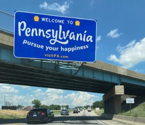 State sign for Pennsylvania hangs over the Interstate.