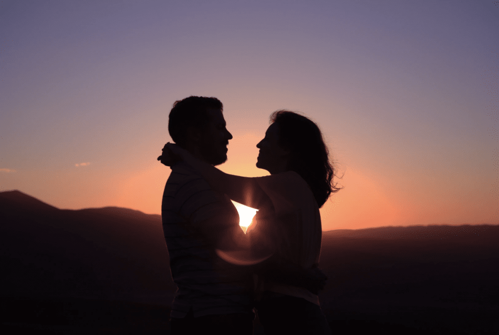 couple standing together against the backdrop of a sunset