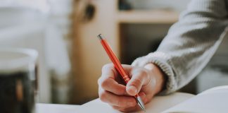 Person's hand about to write in a journal