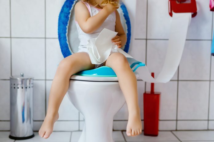 child sitting on a toilet with toilet paper in hand