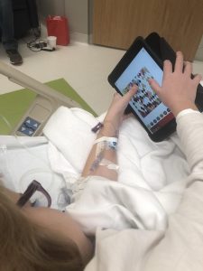 girl in hospital bed playing on iPad