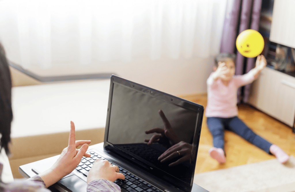 woman on laptop waving finger at child in the background