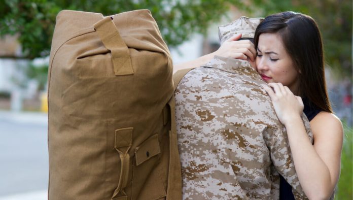 woman hugging a soldier with a military bag