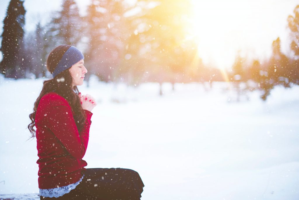 woman sitting with eyes closed in snow and sunshine
