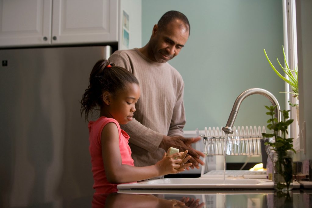 father and daughter washing hands at a kitchen sink