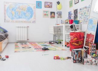 children's room with posters and map on the wall, toys cluttered on the floor and dresser, and a messy bed