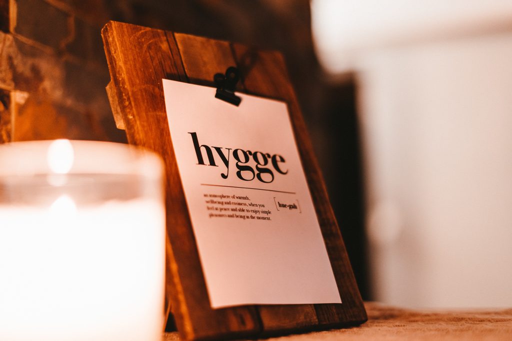 candle and wood board holding a paper that says "hygge"