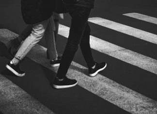 black and white photo of two people walking in a crosswalk