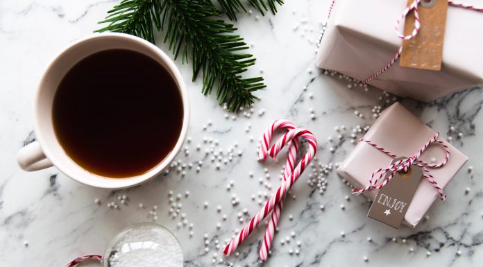 cup of tea, candy canes, wrapped gifts, and pine branch evoking a holiday feeling