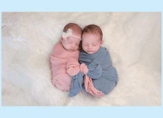 twin babies in pink and blue wraps on a white fluffy blanket