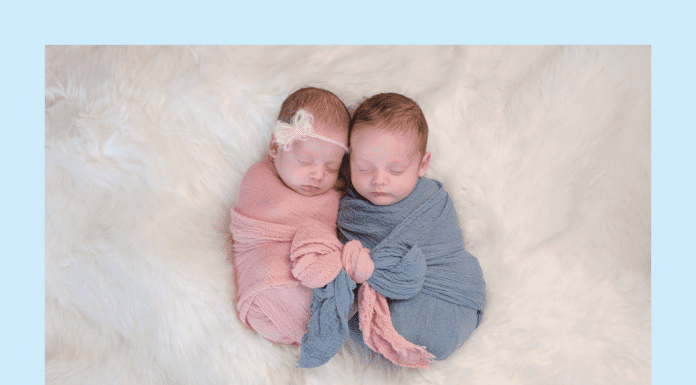 twin babies in pink and blue wraps on a white fluffy blanket