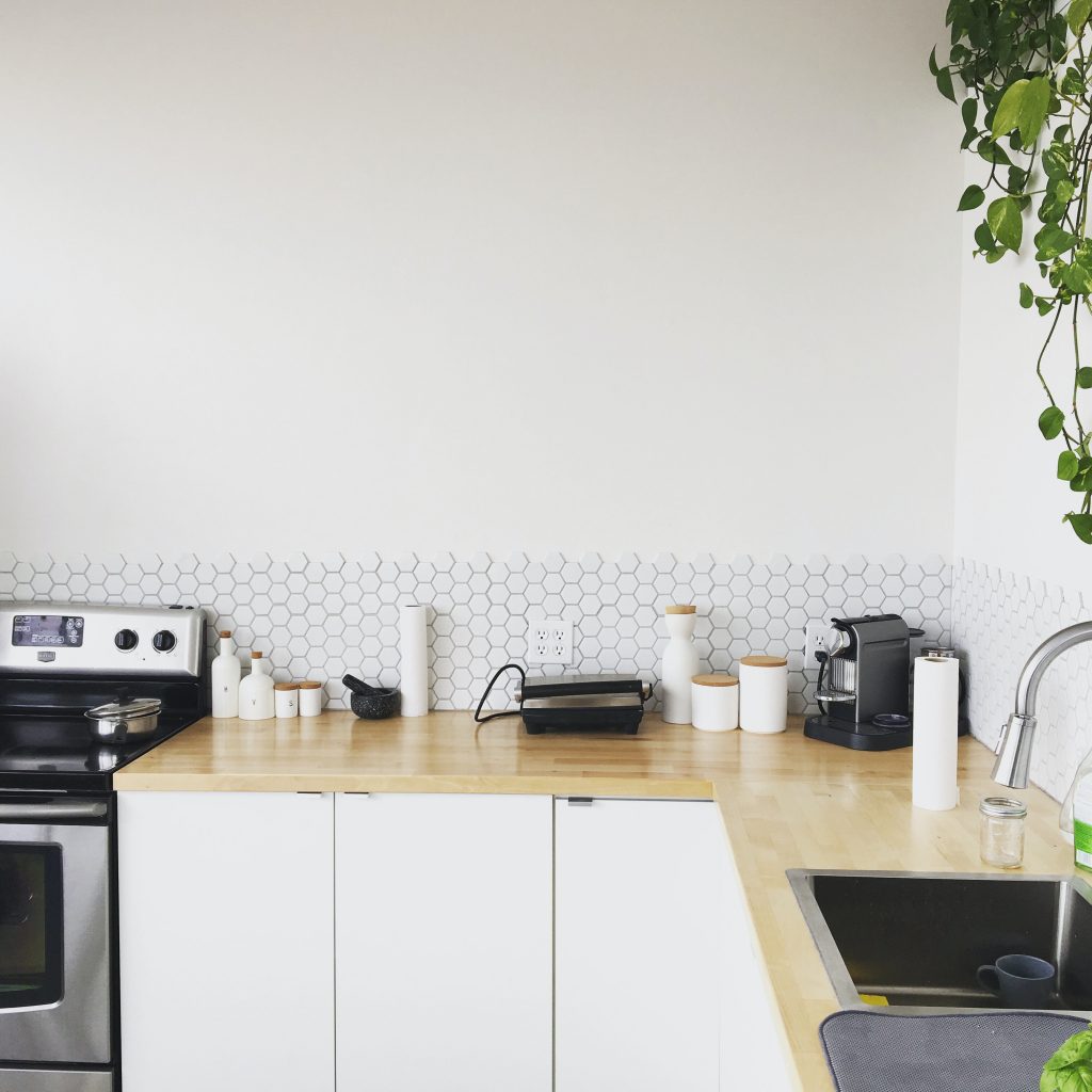 tidy kitchen with white jars, coffee maker, and sink