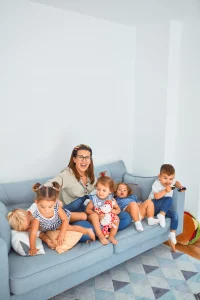 mother sitting on a couch with 5 small children