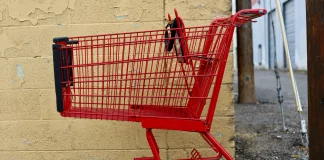 red shopping cart parked next to a yellow wall