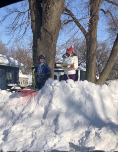 2 kids playing at the top of a snowdrift