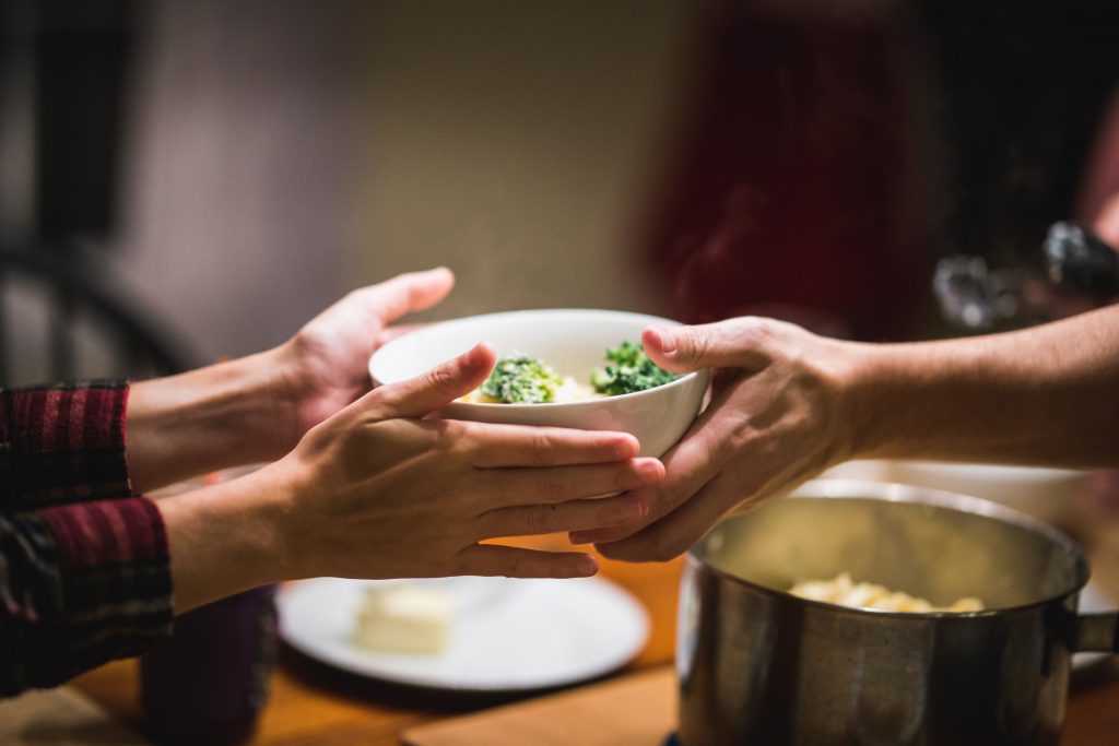 hands sharing a bowl of food at a table