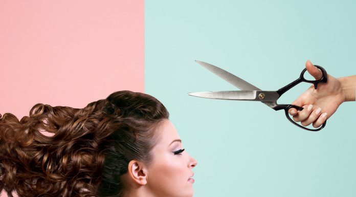 A woman is looking straight ahead while scissors are above her head