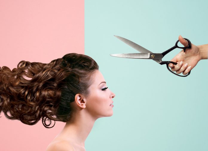 A woman is looking straight ahead while scissors are above her head