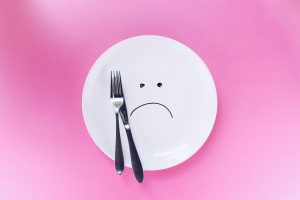 empty plate with a sad face and silverware on it