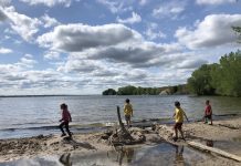 4 kids run across a beach at a lake