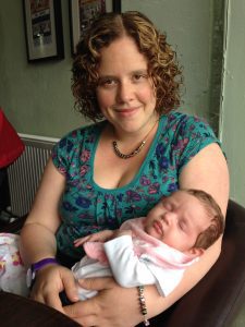 The author, Jenny, is smiling at the camera and holding her baby in her arms. The baby is asleep.