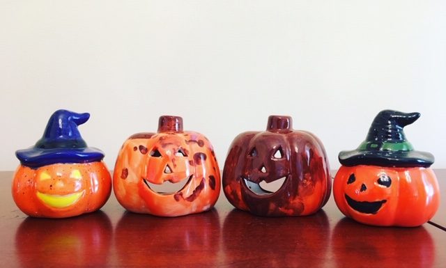 4 ceramic pumpkins are in a row. They have all been handprinted.