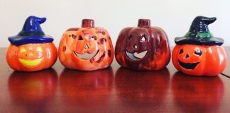 4 ceramic pumpkins are in a row. They have all been handprinted.