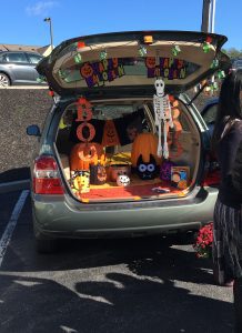 The trunk of a car is decorated for Halloween with black and orange decorations.