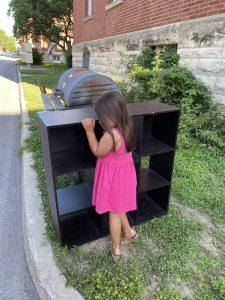 Child hugging bookshelf set on the curb to be picked up and thrown away